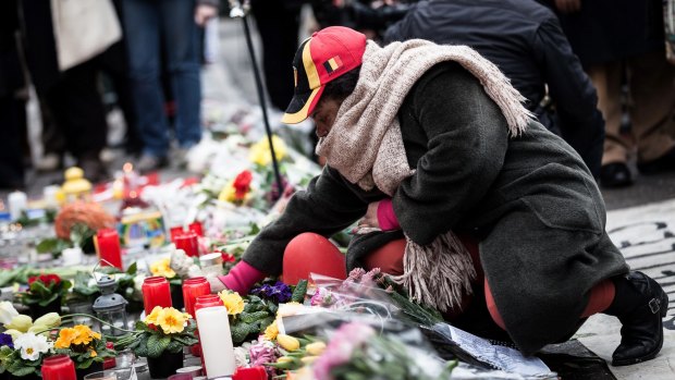 A woman lights a candle at a memorial for victims of attacks in Brussels on Wednesday, March 23.