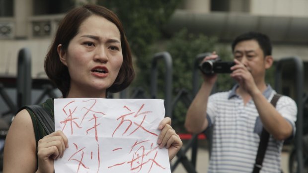 Li Wenzu, wife of imprisoned lawyer Wang Quanzhang, holds a sign that reads "Release Liu Ermin" outside the Tianjin court. Liu Ermin is the wife of one of the arrested activists.