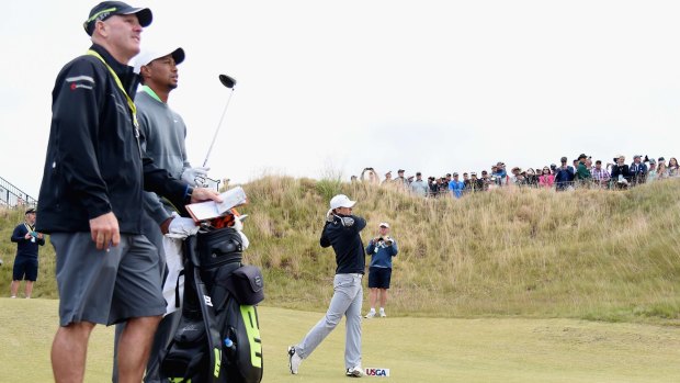 Tiger on his tail: Jordan Spieth hits a tee shot during a practice session at Chambers Bay, watched by Tiger Woods and a caddy.