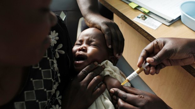 A mother holds her baby as she receives a new malaria vaccine as part of a trial in Kombewa,  Western Kenya in 2009. 