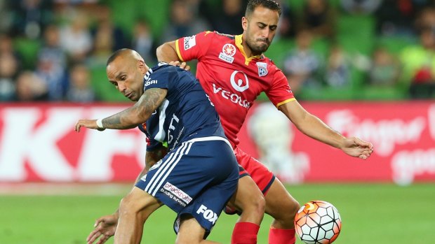 Archie Thompson of the Victory and Tarek Elrich of United fight for possession.