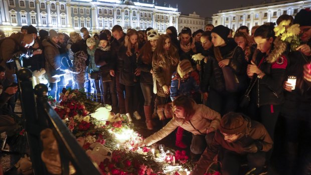 People light candles on a national mourning for the plane crash victims at Dvortsovaya Square in St Petersburg.