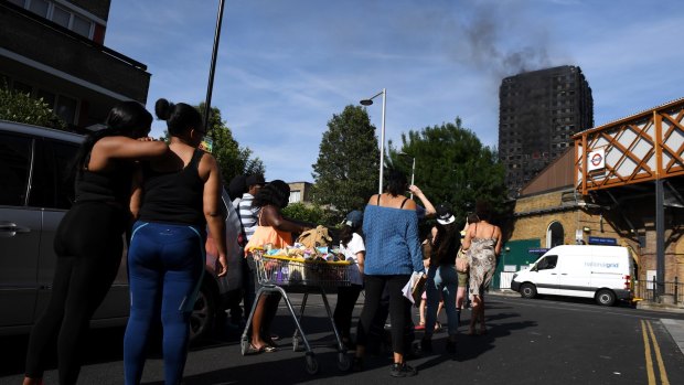 People look on from Latimer Road Station at the smoking 24-storey Grenfell Tower block.