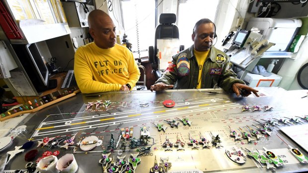 Flightdeck operators organise figurines on a 'ouija board' on-board the USS Ronald Reagan.