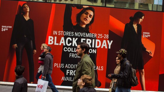 Shoppers pass a retail store as they walk along Fifth Avenue on Black Friday in New York. 