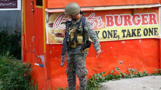 A Philippine marine signals his men to slow down as they near a corner at the frontline in Marawi city on Sunday.