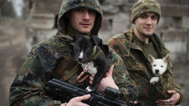 Ukrainian servicemen put their dogs under their jackets to stay warm in Mariupol in January. 