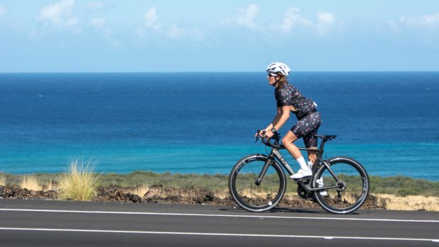 A woman wearing Fondo cycling gear rides a Kukio bike.