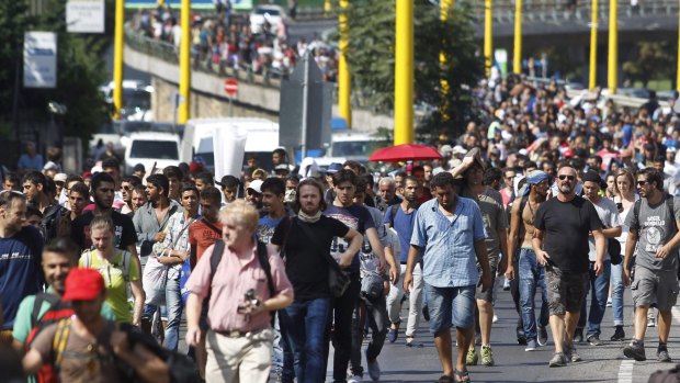 A defiant march to Germany: Migrants walk along the Hegyalja Street in Budapest on Thursday before Hungary set up bus transport to take them.