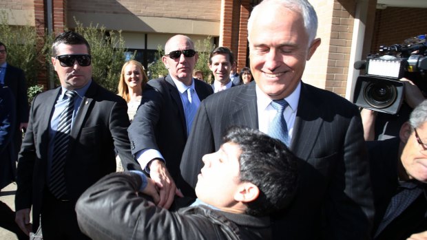 Chas Licciardello from The Chaser TV comedy show falls at the feet of Prime Minister Malcolm Turnbull as part of a trust stunt in western Sydney.