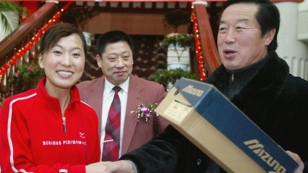 Olympic long-distance running champion Wang Junxia (L) shakes hand with former China track coach Ma Junren at the opening of Wang's Running Club in 2005 in Shenyang, China.