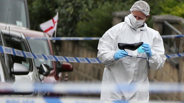 A forensics officer looks at a female shoe, at the scene after Labour MP Jo Cox was killed in an attack in her constituency.