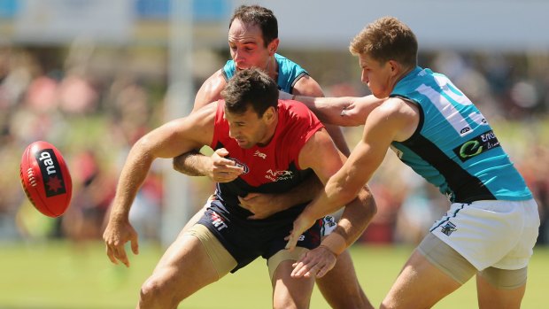 Port's Matt White (right) joins teammate Matthew Broadbent in tackling Cameron Pederson of the Demons. White later tore a pectoral muscle and will  miss at least half the season.