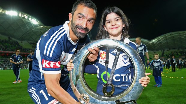 Fahid Ben Khalfallah and his daughter celebrate with the A-League trophy.