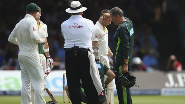 Ouch: Chris Rogers is treated by Australian team doctor Peter Brukner after being struck on the helmet by a delivery from James Anderson.