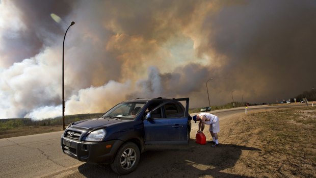 An evacuee puts gas in his car on his way out of Fort McMurray on Wednesday.