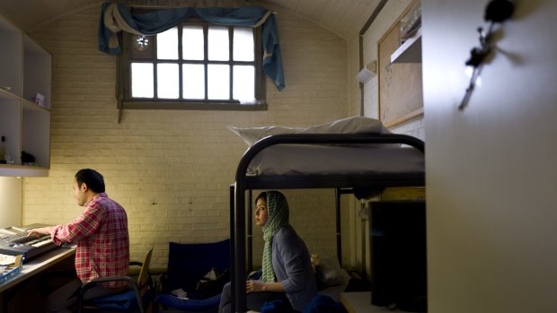 Afghan refugee Hamed Karmi, 27, plays keyboard next to his wife Farishta Morahami, 25, sitting on a bed inside their room at the former prison of De Koepel in Haarlem.