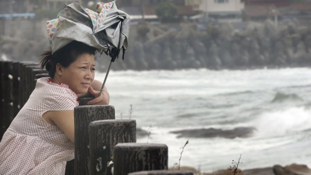 A woman braves the winds as she watches waves from approaching Typhoon Soudelor in Keelung, northeastern Taiwan,  on Friday