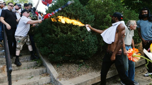A counter-demonstrator uses a lighted spray can against a white nationalist demonstrator.
