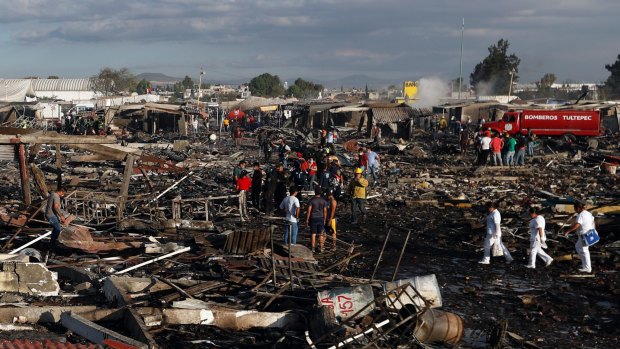 Firefighters and rescue workers walk through the scorched ground of Mexico's best-known fireworks market.