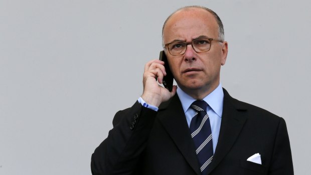 French Interior Minister Bernard Cazeneuve makes a phone call before the traditional Bastille Day military parade in Paris.
