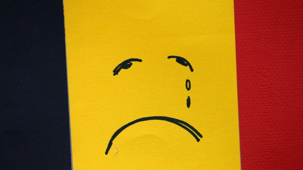 A sad face is drawn on a Belgian flag near Maelbeek metro station after Tuesday's attack.