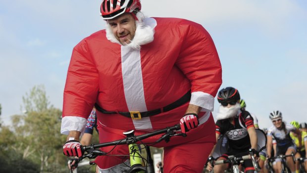 Canberra's Santa (aka Andrew Blair) rides with a group of cyclists past the Lodge on Christmas Day.