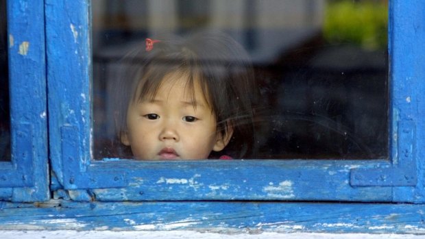 In this photo released by the World Food Program a North Korean child peers through a window at a creche in Hyangsan.