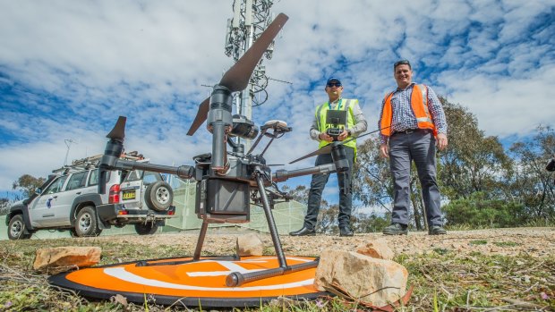 Chief remote pilot Rob Harvey (yellow vest) and UAV pilot Clint Dickson (orange vest) with one of the drones.