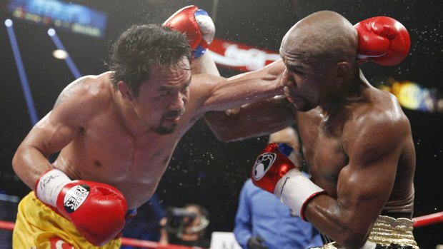 Manny Pacquiao, left, trades blows with Floyd Mayweather.