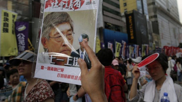 A protester raises a booklet with a picture of bookseller Lam Wing-kee on the cover.