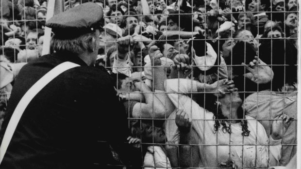 An ambulance worker looks on as Liverpool fans are crushed against a barrier.