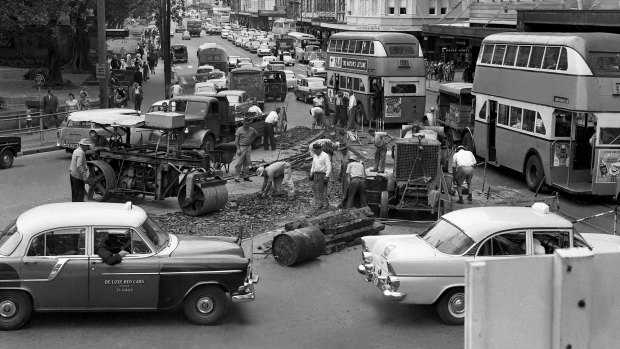 "But for Sydney motorists, even two years seems a long time to wait before they can expect a smoother ride..." Traffic jams in Elizabeth Street on 12 December 1961, due to workmen removing tram tracks.
