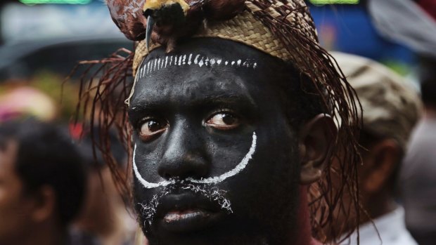 A Papuan activist in traditional headwear protests against US mining giant Freeport-McMoRan which activists say is siphoning off the region's wealth and giving it little in return.