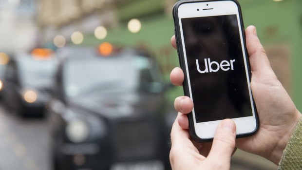 An ongoing battle: A commuter uses Uber in view of a line of black cabs in London, UK.