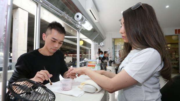 Nail artist Jonny Diep Pham working on Tara Micallef's nails in his Penrith salon Nailicious. 