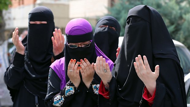 Uighur women pray after riot police used pepper spray to push back a group of Uighur protesters outside the Chinese embassy in Ankara on Thursday.