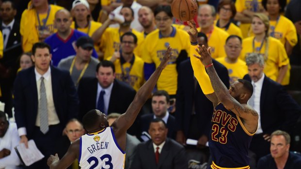 LeBron James shoots under pressure from Draymond Green.