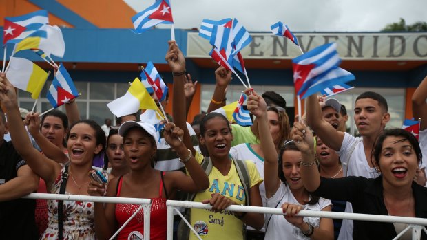 Youngsters wave Cuban and Vatican flags after Pope Francis arrives in Havana.