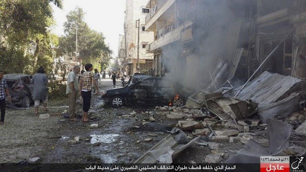 In this photo released Monday by the Rased News Network, affiliated with Islamic State militants, people gather at the site of an airstrike in Al-Bab on the outskirts of Aleppo, Syria. 