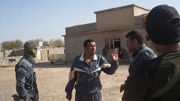 A local resident talks to Iraqi Federal Police officers after they entered Shura, some 30 kilometers south of Mosul, Iraq.