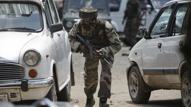 An Indian soldier takes cover behind cars in Dinanagar.