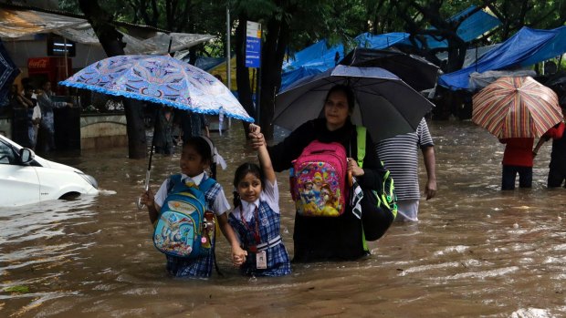 School children wade through a waterlogged street in Mumbai on Tuesday.