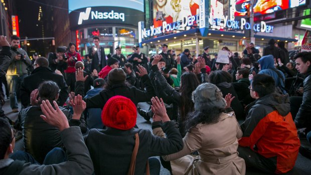 Demonstrators sit down with their hands up in New York's Times Square.