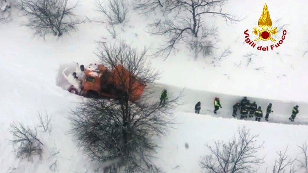 Rescuers try to clear a path to the hotel in heavy snow on Thursday.