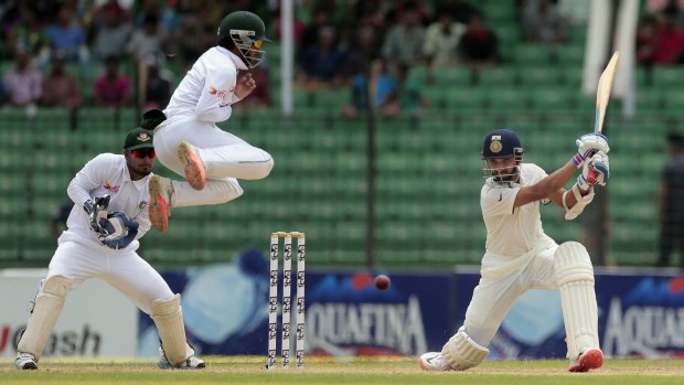 India's Ajinkya Rahane plays a cover-drive as Bangladesh's Mominul Haque leaps to avoid getting injured on the third day of the Test.
