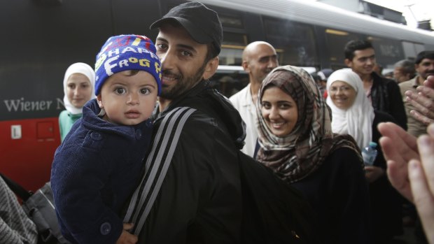 Migrants smile as they arrive safely at Westbahnhof Station in Vienna on Saturday.