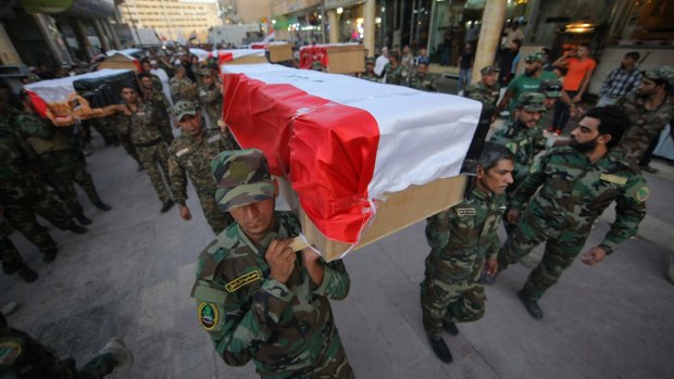 Members of Shiite group Asaib Ahl al-Haq, or "League of the Righteous", carry the coffins of 10 Iraqi soldiers who were killed by Islamic State militants when they overran Camp Speicher last year.