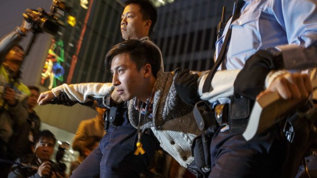 A demonstrator is taken away by Hong Kong police officers.