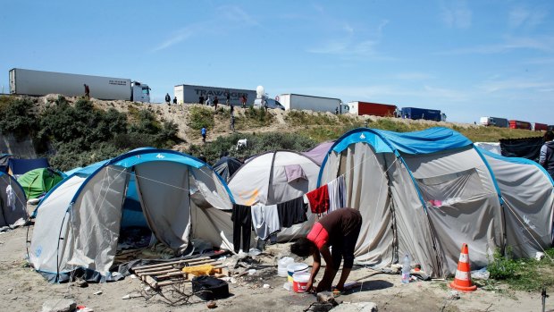 A migrant washes her feet at a makeshift camp known as the "jungle", in Calais, as trucks queue up to enter the Channel Tunnel on Wednesday.